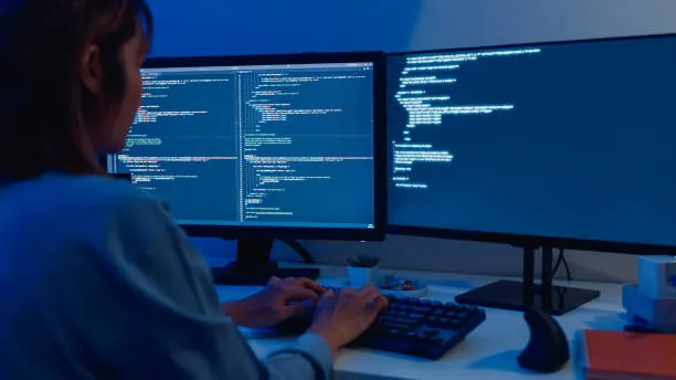 Desenvolvedor analisando código em múltiplas telas com Python e JavaScript, tomando decisão de projeto